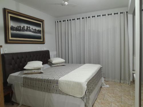 a bedroom with a large bed with white sheets at Hotel e Pousada Ciconha-são Lourenço MG in São Lourenço