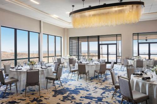 a banquet room with tables and chairs and windows at Delta Hotels by Marriott™ Virginia Beach Waterfront Suites in Virginia Beach
