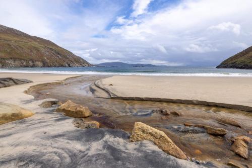 a sandy beach with rocks and the ocean at Detached cottage overlooking lake in Connemara in Ballyconneely