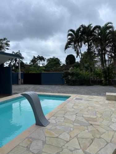 a swimming pool with a metal rail next to a stone patio at Flat Beija-Flor - 500m da praia in Ubatuba