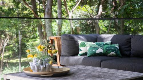 Un sofá gris sentado en una mesa con flores. en Elegant Abode Only Moments To Macmasters Beach, en Macmasters Beach