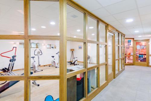 a gym with glass windows and exercise machines at Lagrange Vacances Les Fermes Emiguy in Les Gets