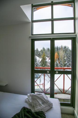 a bedroom with a window looking out at a snow covered yard at Alpenglow Lodge by Elevate Vacations in Whistler