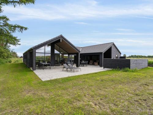 a black house with a patio in a field at 5 star holiday home in Otterup in Otterup