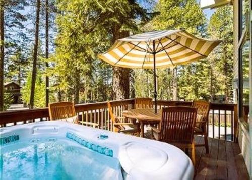 a hot tub on a deck with a table and an umbrella at Sandy Shores Villa in Tahoe Vista