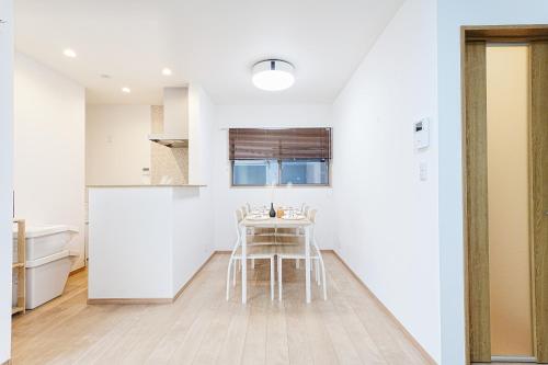 a white kitchen with a table and chairs at Manere in Tokyo