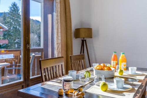 a dining room table with a bowl of oranges and juice at Lagrange Vacances Les Fermes Emiguy in Les Gets