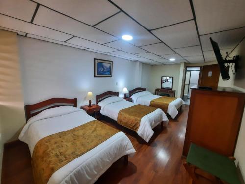 a group of four beds in a room at Hotel El Lago in Paipa