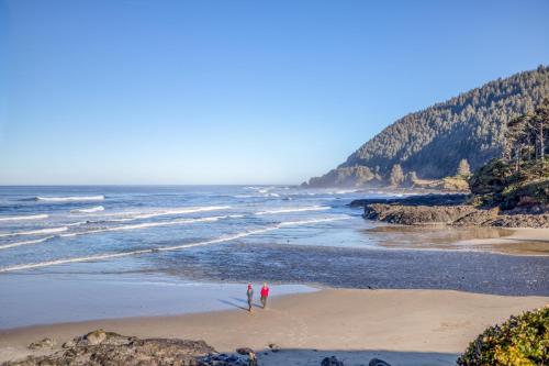 two people standing on a beach near the ocean at The Sea Anemone - Meredith Lodging in Yachats