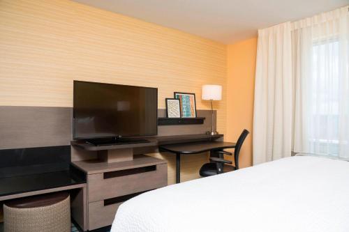 a hotel room with a bed and a desk with a television at Fairfield Inn & Suites by Marriott Medina in Medina