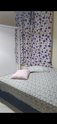 a bed with a pink pillow sitting on top of it at Recanto Quaresma in Cabo Frio