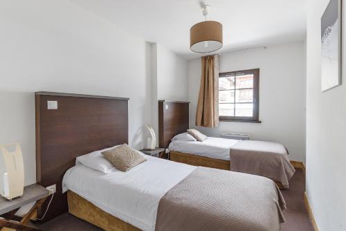 a hotel room with two beds and a window at Lagrange Vacances Les Fermes Emiguy in Les Gets