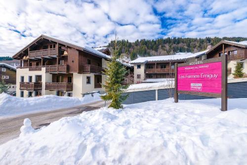 a sign in the snow in front of a building at Lagrange Vacances Les Fermes Emiguy in Les Gets