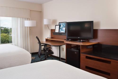 a hotel room with a desk with a television and a bed at Fairfield Inn Charlotte Gastonia in Gastonia