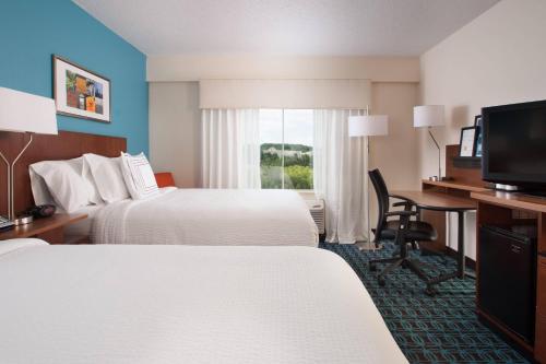 a hotel room with two beds and a desk and a television at Fairfield Inn Charlotte Gastonia in Gastonia