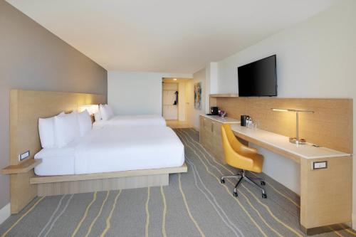 a hotel room with a large bed and a desk at Delta Hotels by Marriott Daytona Beach Oceanfront in Daytona Beach