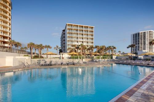 a large swimming pool with chairs and a hotel at Delta Hotels by Marriott Daytona Beach Oceanfront in Daytona Beach
