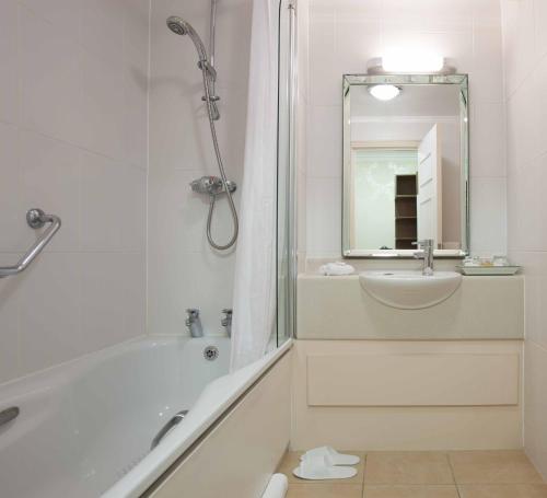 a white bathroom with a shower and a sink at The Manor Elstree in Elstree