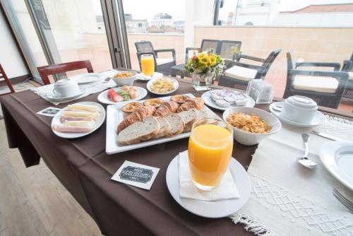 una mesa con alimentos para el desayuno y zumo de naranja en ella en Porto Coliseum Hotel, en Oporto