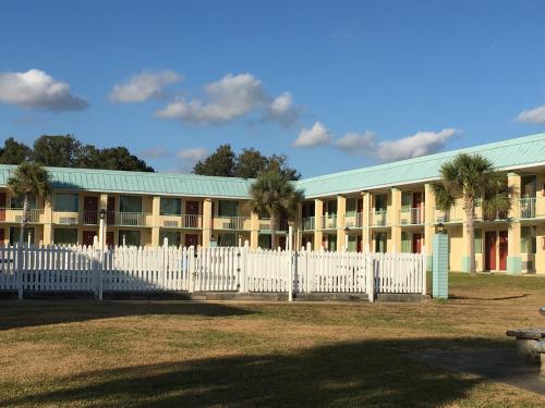 a building with a white fence and palm trees at Garden Inn & Suites in Pensacola