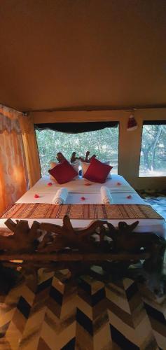 a bedroom with a large bed with red pillows at Yala Podi Hoona Bush Camp in Yala