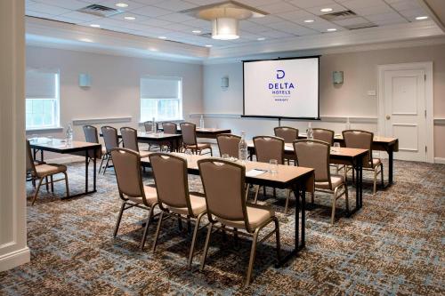 a conference room with tables and chairs and a screen at Delta Hotels by Marriott Basking Ridge in Basking Ridge
