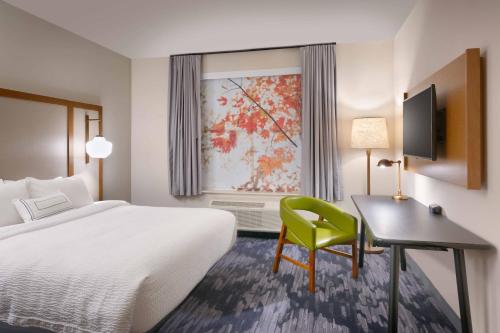 a hotel room with a bed and a desk with a green chair at Fairfield Inn & Suites by Marriott Rockport in Rockport