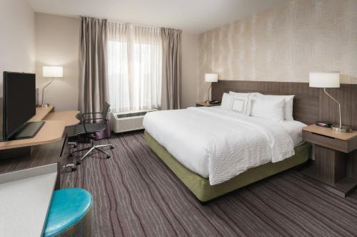 a hotel room with a bed and a flat screen tv at Fairfield Inn & Suites by Marriott Chicago Schaumburg in Schaumburg