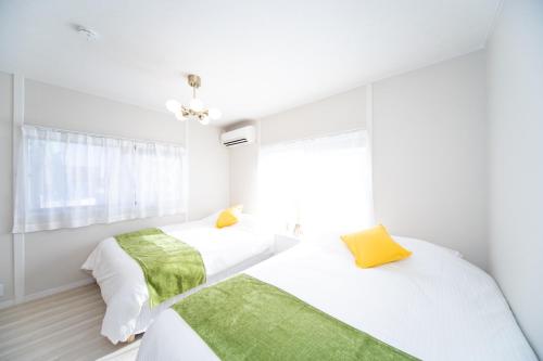 two beds in a white bedroom with a window at Miraie Yokkaichi Nishishinchi 2 in Yokkaichi