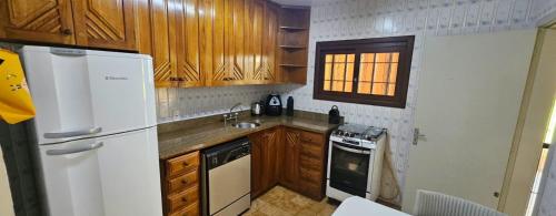 a kitchen with a white refrigerator and wooden cabinets at Casa a duas quadras do mar próxima ao centro in Capão da Canoa