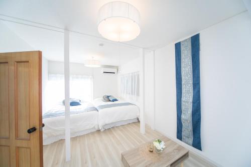 a white bedroom with a bed and a table at Miraie Yokkaichi Nishishinchi 2 in Yokkaichi