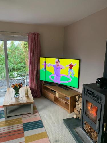 a living room with a flat screen tv and a fireplace at Spacious romantic party cottage with log burner and Ultrafast Fibre near pub Pet friendly in Cross Hands