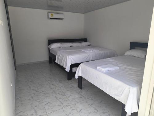 two beds in a room with white walls and tile floors at Villas Campestres las Heliconias in Villavicencio