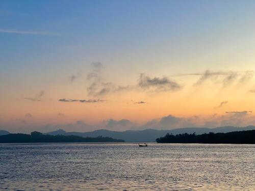 a boat in the middle of the water at sunset at Bankruchaem Homestay Kohpu in Ban Klang