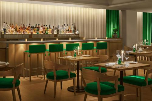 a restaurant with wooden tables and green chairs at The Tokyo EDITION, Ginza in Tokyo
