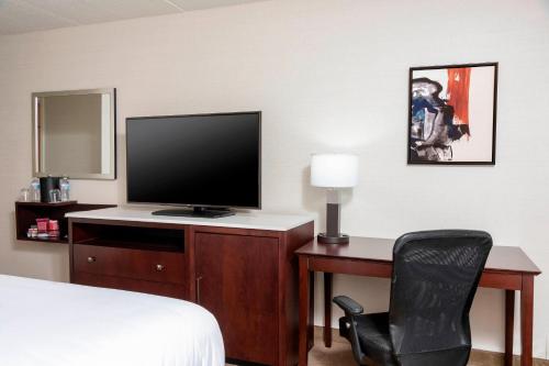 a hotel room with a desk with a television and a chair at Delta Hotels by Marriott Kalamazoo Conference Center in Kalamazoo