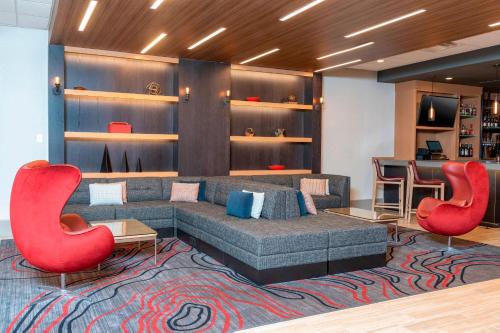 a living room with a couch and two red chairs at Delta Hotels by Marriott Kalamazoo Conference Center in Kalamazoo