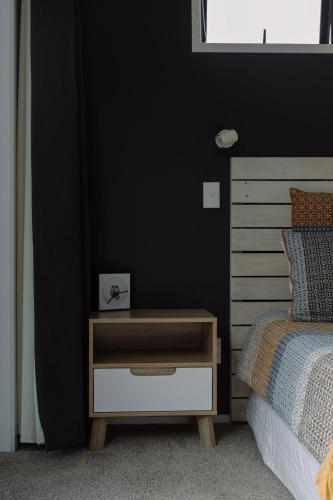a bedroom with a bed and a nightstand with a drawer at Barrique Studio with Sauna at Barrelled Wines Raglan in Raglan
