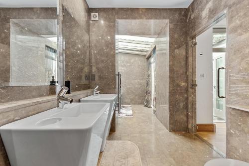 a bathroom with three sinks and two mirrors at 250 SqM MEGA MANSION in London