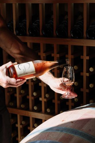 a person holding a bottle of wine and a glass at Barrique Studio with Sauna at Barrelled Wines Raglan in Raglan