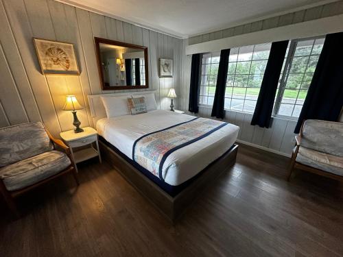 a bedroom with a bed and a chair and windows at Tillicum Beach Motel - Formerly Deane's Oceanfront Lodge in Yachats