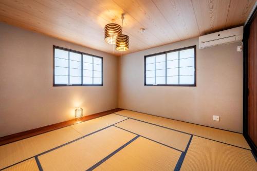 an empty room with two windows and a door at 臨空の宿 MARUYA Izumisano in Izumi-Sano