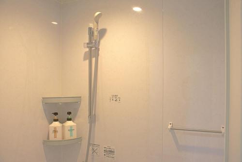 a bathroom with a shower and a toilet with two bottles at オレンジの風 in Imabari