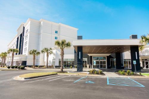 a large white building with palm trees in a parking lot at Delta Hotels by Marriott Columbia Northeast in Columbia