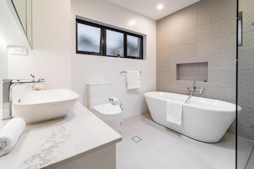 a white bathroom with a tub and a toilet at Private Paradise with Stunning Views in Taren Point