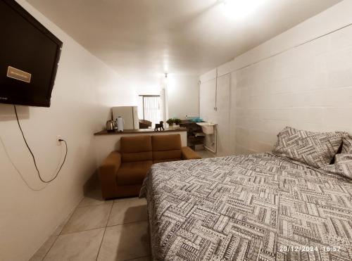a bedroom with a bed and a couch and a television at MicroAP na cidade do Cristo in Encantado