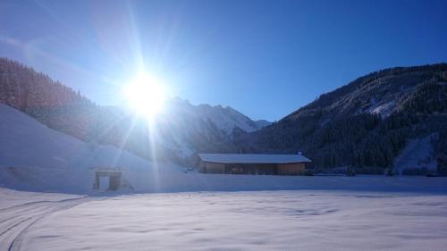 a building in the snow with the sun behind it at Hotel Sportalm in Gerlos