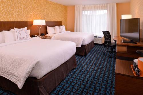a hotel room with two beds and a flat screen tv at Fairfield Inn & Suites by Marriott Plymouth White Mountains in Plymouth