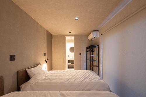 a bedroom with a white bed and a window at Cosmique Chalet Hakuba in Hakuba