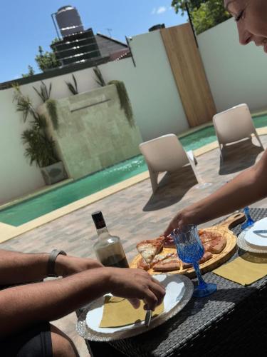 a woman sitting at a table with a plate of pizza at LyL HURLINGHAM alojamiento privado in Hurlingham